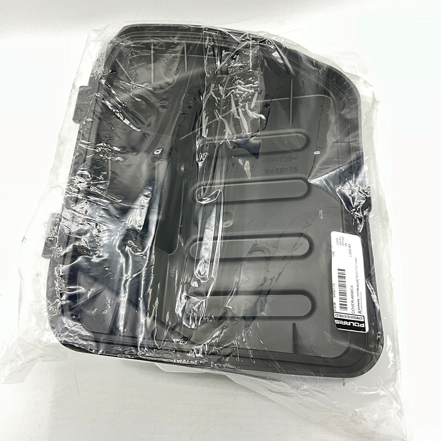 Black molded plastic airbox cover with horizontal ridges, sealed in clear plastic wrap.