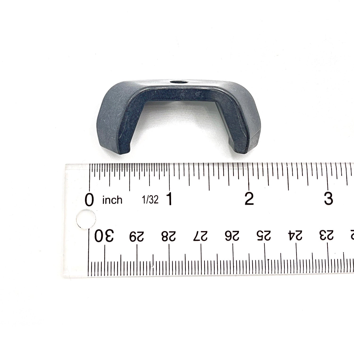 Small black plastic button cover with a U-shaped design, placed next to a ruler for scale.