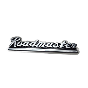 A chrome car emblem with "Roadmaster" in retro cursive, styled like the Badge Roadmaster Flat by Polaris, shown on a white background.