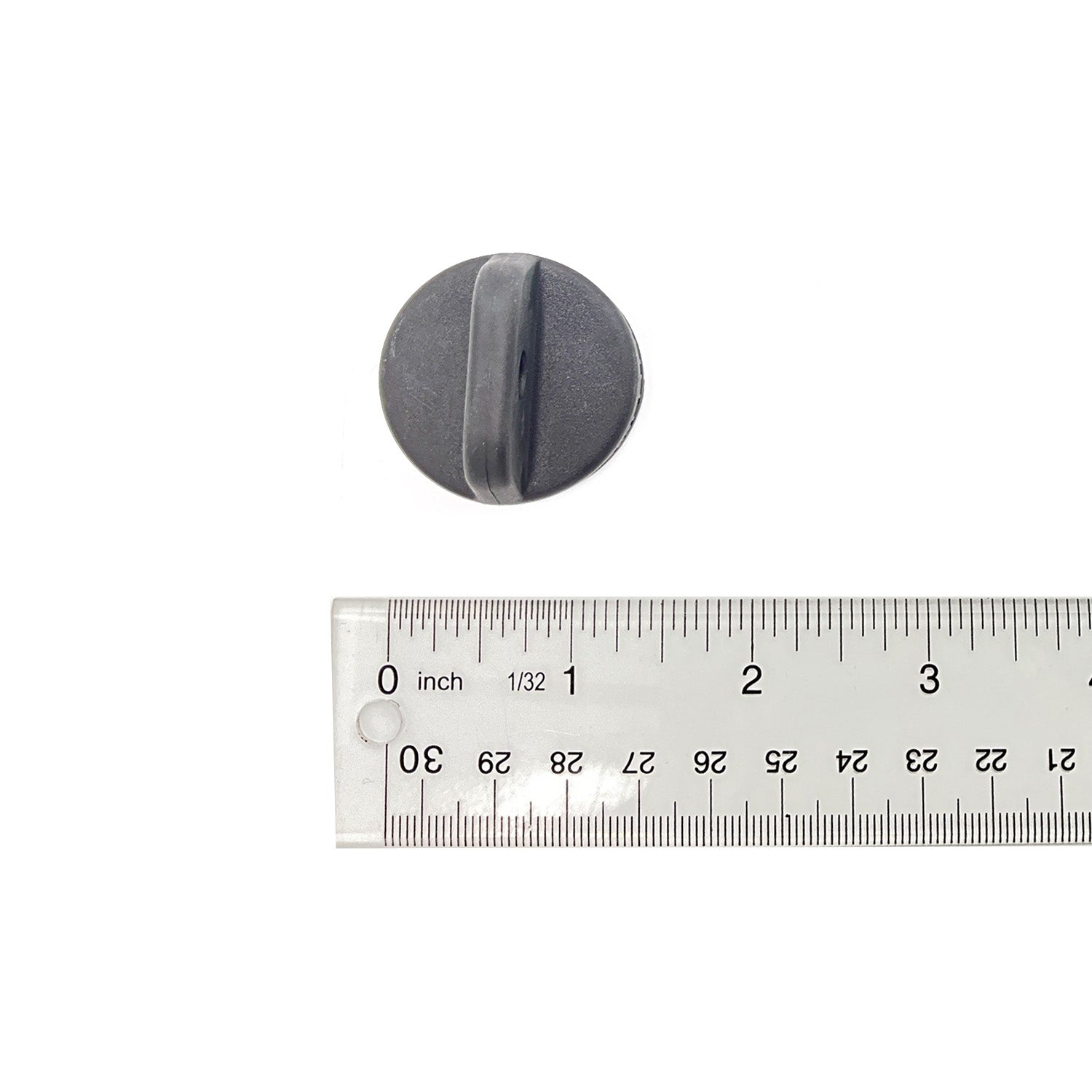 Black round plastic key cover knob with a vertical grip slot beside a clear ruler showing size under 1.5 inches.