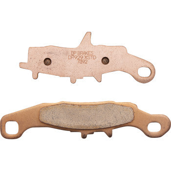 Two Kawasaki - Suzuki Sintered Brake Pads by Dp Brakes are shown—one spotlights its friction material, the other displays the solid backing plate. Both pads have mounting holes at each end and feature durable sintered metal construction.