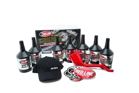 The Big Twin Powerpack Oil Change Kit 20W60 by Red Line includes Motorcycle Oil and V-Twin Transmission Oil bottles, a black cap with RED LINE OIL text, a red funnel, Red Line stickers, and a branded product box in the background.