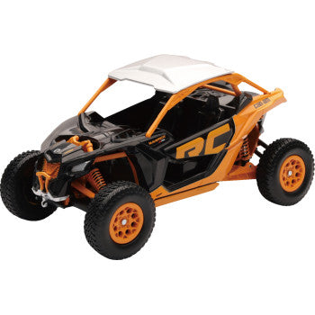The Can-Am Maverick X3 XRC Turbo 1:18 scale by New Ray Toys, in black and orange with large tires and visible suspension, features a white roof and is displayed on a white background.