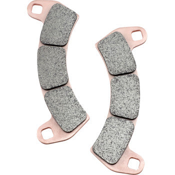 Two SXR Brake Pads by Ebc with textured gray friction surfaces and copper-colored backing plates, each featuring three mounting holes and three raised friction blocks. The race-derived pads are oriented in opposite directions.