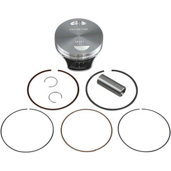 The Yamaha Piston Kit 74.00 mm by Wiseco includes a forged metal piston, wrist pin, two circlips, and four piston rings—engineered for superior performance and strength-to-weight ratio. All parts are displayed neatly on a white background.
