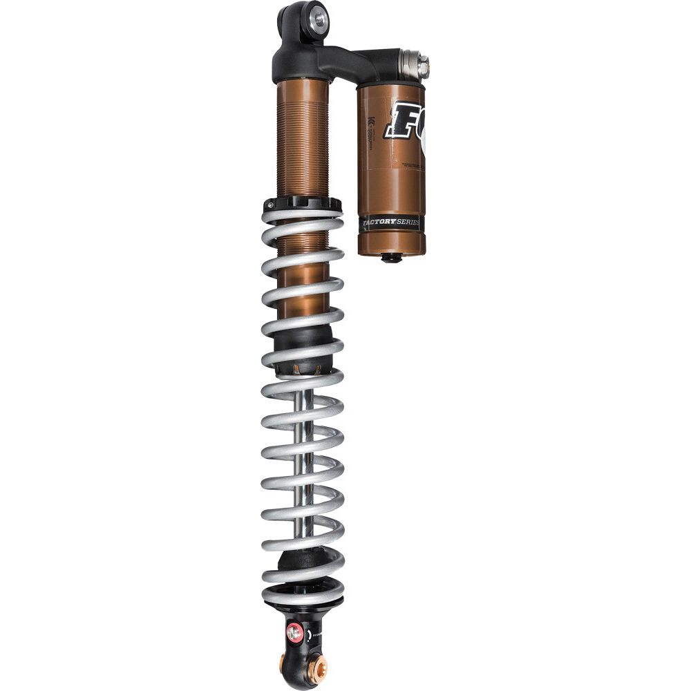A close-up of the Yamaha Grizzly Fi 1.5 Podium RC2 Utility Shock by Fox, featuring a bronze Kashima Coat finish, external reservoir, and silver coil spring for advanced suspension on rough terrain.