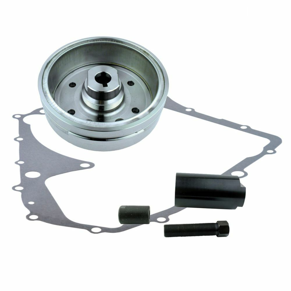 Silver metal flywheel, gray irregular-shaped gasket, and two black cylindrical mounting components on white background.