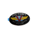 Oval black metal fuel tank badge with silver trim, featuring gold wings and a red and blue "V" logo, labeled "Victory.