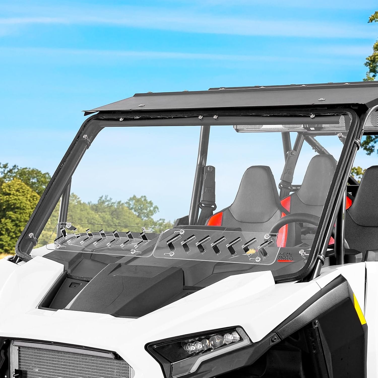A close-up of a white and black off-road vehicle with a vented windshield and two seats, parked outdoors, showcases the Polaris RZR XP 1000 /4 Front Full Windshield by Kemimoto for lasting durability and clear views.