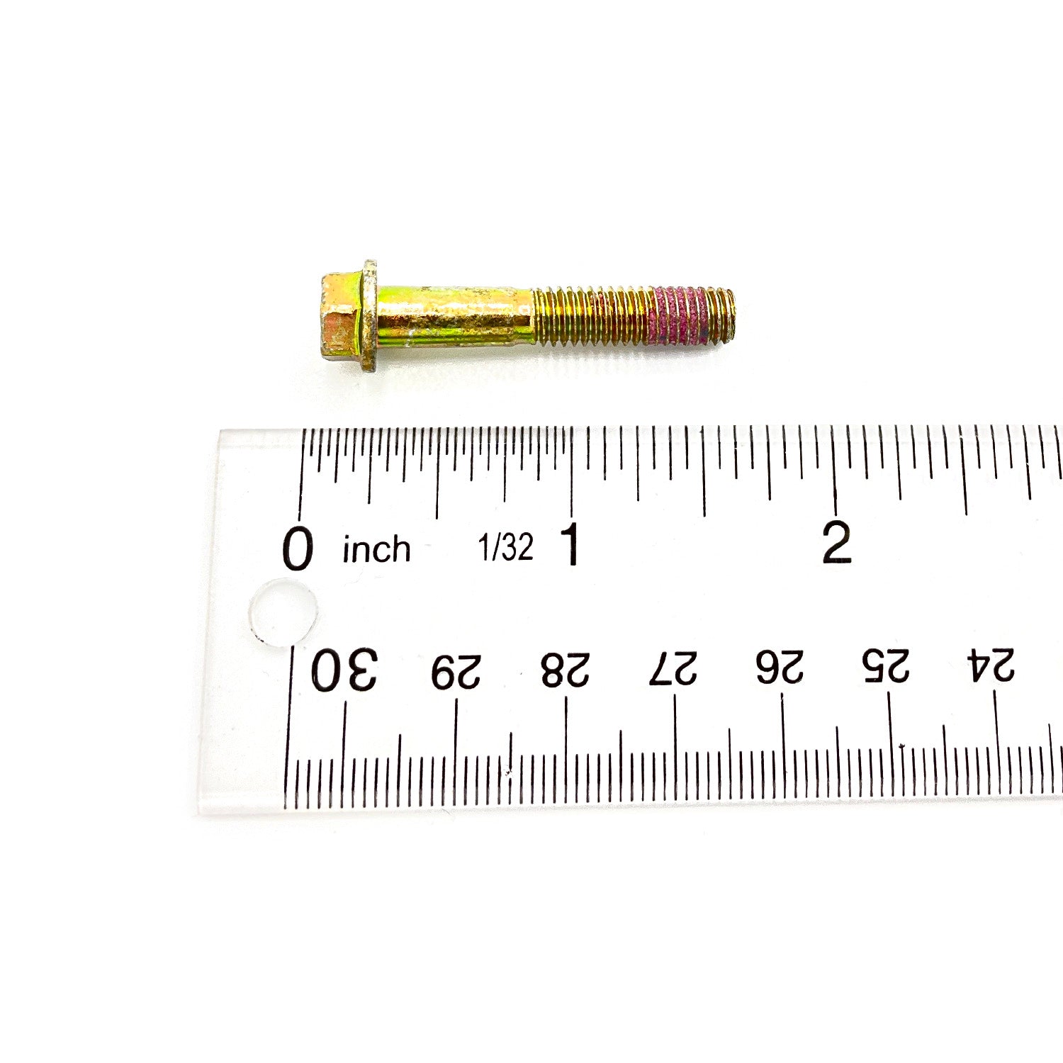 Gold-colored metal screw with hexagonal head and partially threaded shaft next to a clear ruler.