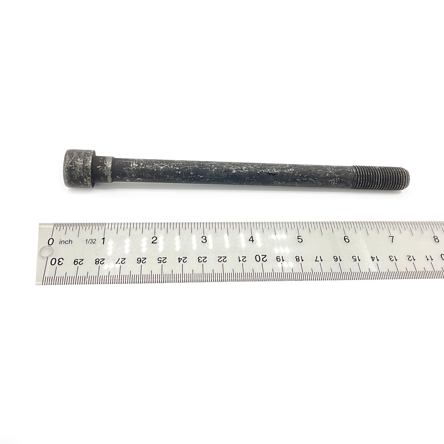 Long black hex flange screw with threaded tip, placed above a 30cm metal ruler.