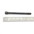 Long black hex flange screw with threaded tip, placed above a 30cm metal ruler.