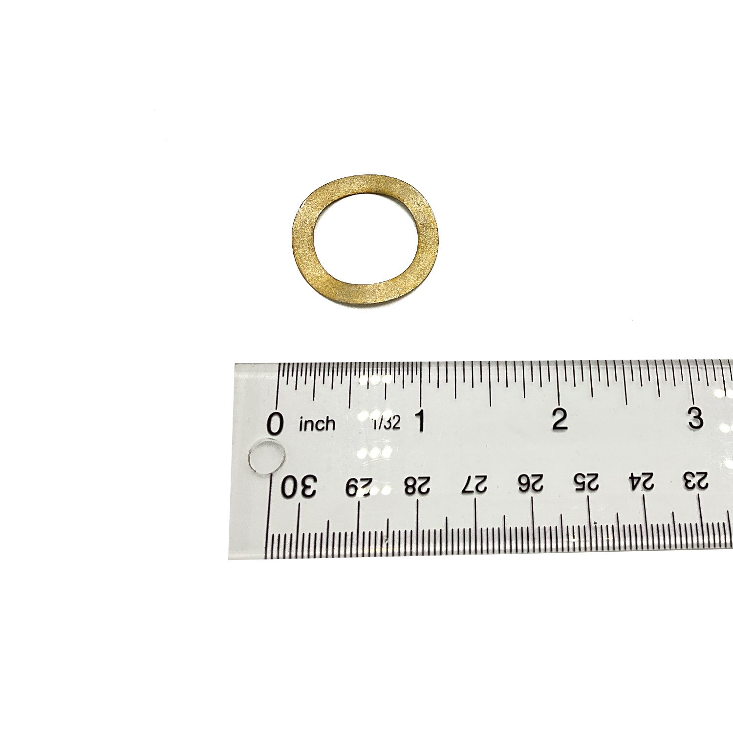 Small brass wave washer with circular shape next to clear plastic ruler showing size under one inch.