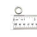 Small silver metal washer measuring approximately half an inch in outer diameter against a white background with a ruler.