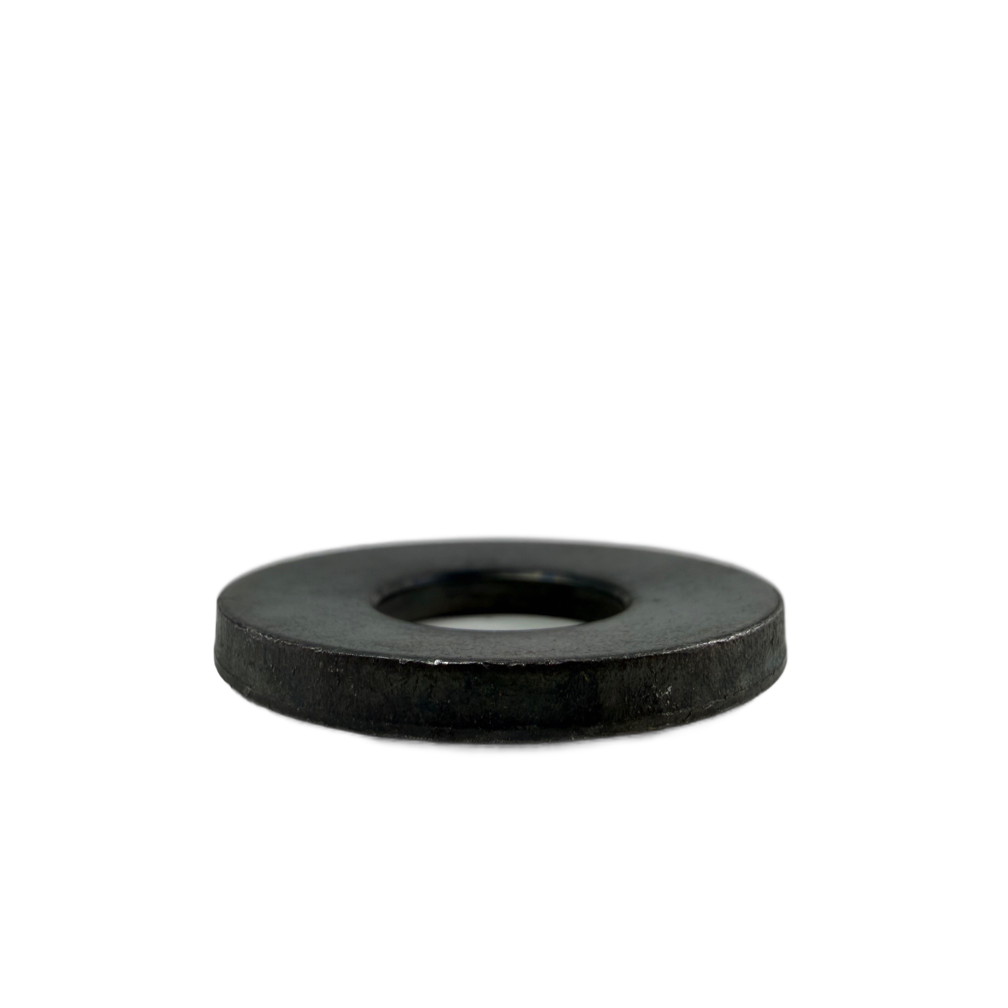 Black metal axle washer with smooth flat surface and central round hole.