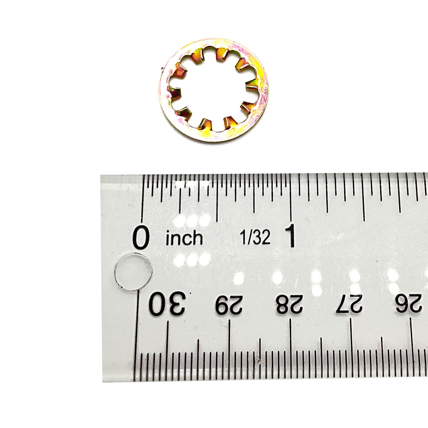 Small circular washer lock with internal teeth, metal with a yellow-gold finish, next to ruler showing about 0.