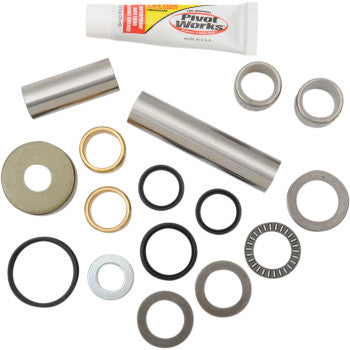Assorted metal bearings, spacers, bushings, washers, black rubber O-rings, and lubricant tube arranged on a white background.