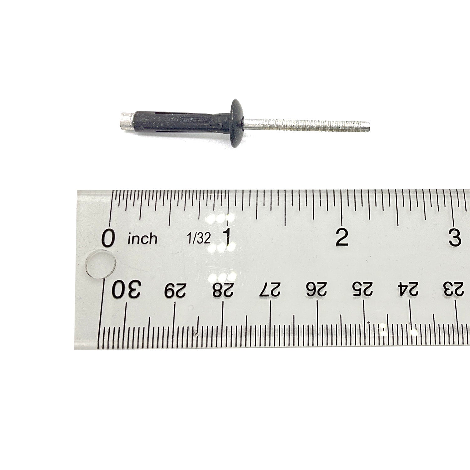 Black and silver rivet next to a metal ruler showing its length at about 2.5 inches.