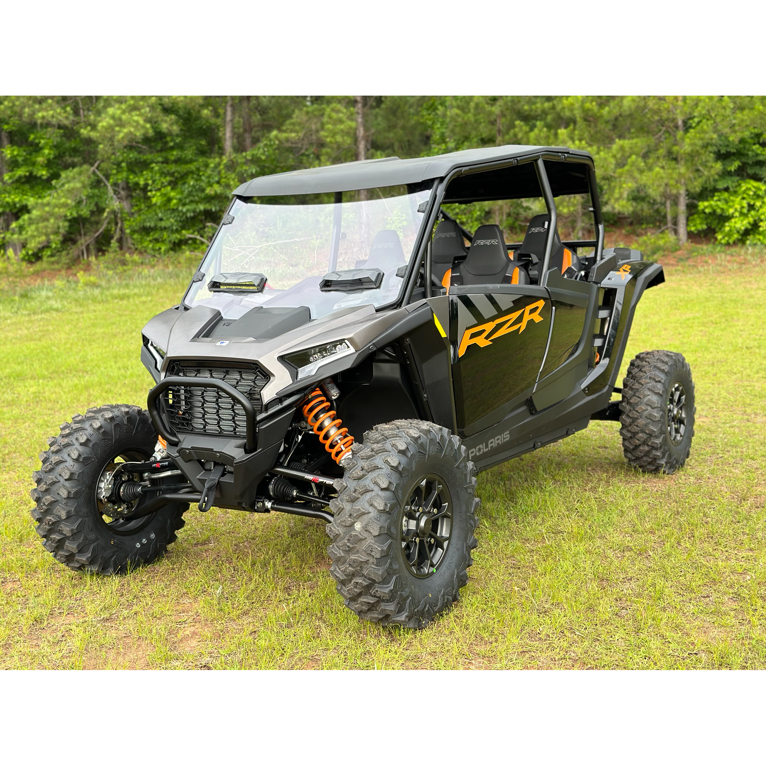 Black off-road side-by-side vehicle with rugged tires and orange coil suspension springs.