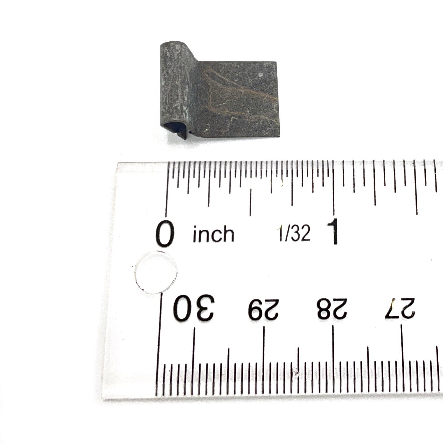 Small black metal U-shaped clip positioned next to a clear ruler showing inch measurements for scale.