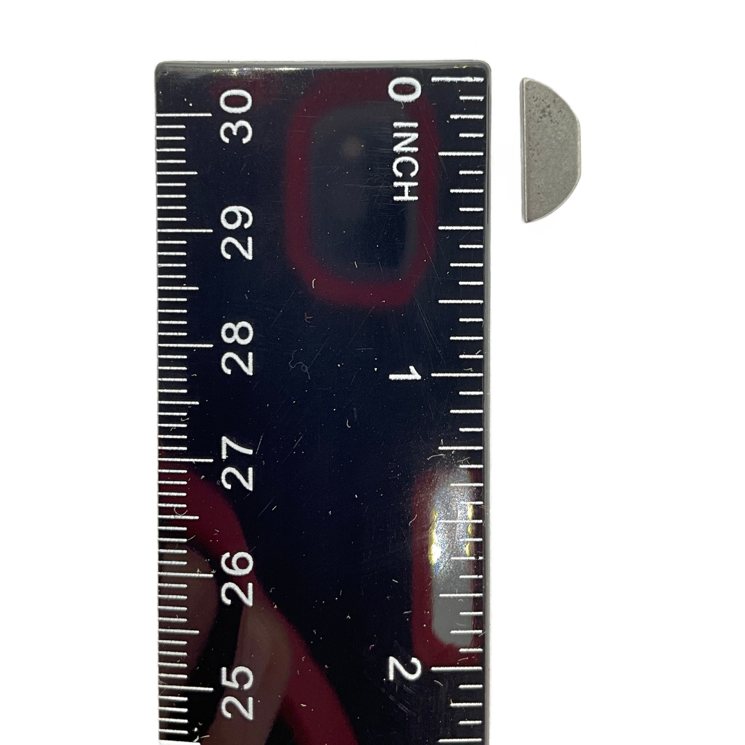 Small metallic semicircular woodruff key beside a black ruler showing size just over half an inch.