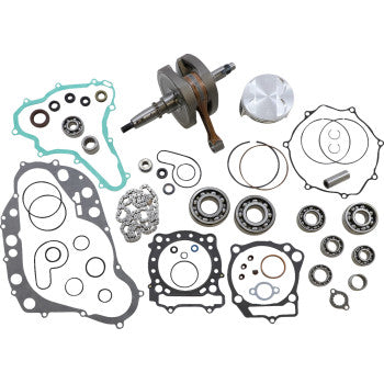 Suzuki engine rebuild kit with metal crankshaft, silver piston, black and green gaskets, and various bearings and seals.