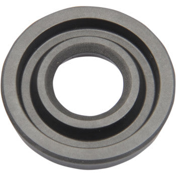 A close-up of the Rear Shock Oil Seal By KYB, showcasing its circular design with an inner and outer ring and a central hole. This OE replacement part appears clean and is photographed against a white background.