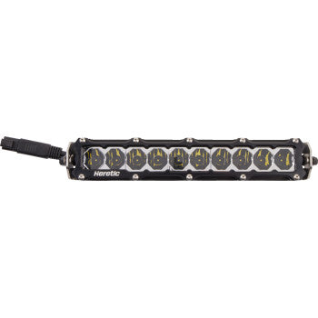 The Shock Tower Light 10" by Heretic features a row of twelve circular CREE LEDs in a rectangular aircraft aluminum housing, "Heretic" displayed below the lights, and a black cable attached to the left side.