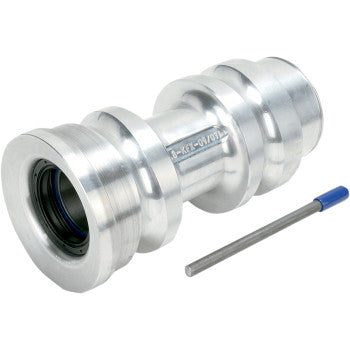 The Axle Carrier Super Twin by Lone Star Racing, a shiny silver metal coupler with grooves and a high-performance seal opening, is shown beside a small cylindrical metal tool with a blue handle.