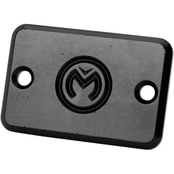 The Master Cylinder Cover Black by Moose Offroad is a rectangular black metal plate with two screw holes and an engraved circular M-X logo, ideal for reservoir covers or other quad accessories.