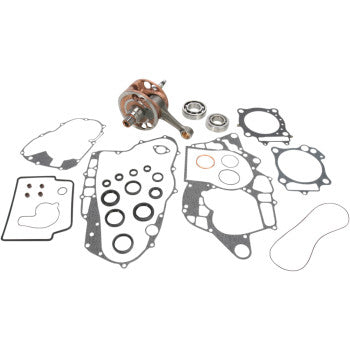 Metal crankshaft with connected rods and multiple black gaskets of various shapes and sizes laid out on a white background.