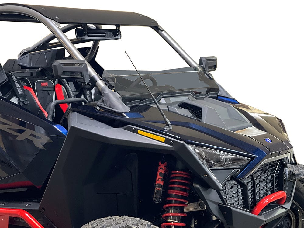 A close-up of a black and blue off-road utility vehicle with red suspension springs, open cabin, black seats with red accents, and a Polaris Pro-R Tinted Short Windshield by Spike for added protection and visibility, against a white background.