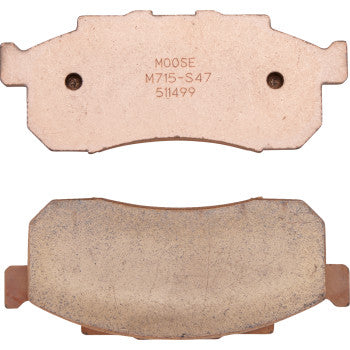 Two rectangular copper-colored metal brake pads with curved edges and small holes, marked with "Moose M715-S47 51499" on one