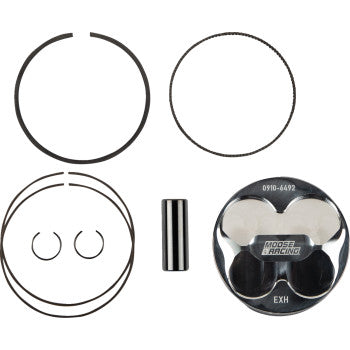 Top-down view of the Suzuki Piston Kit 95.50 mm by Moose Offroad, showing a forged piston with skirt coating, DLC wrist pin, piston rings, and two circlips—all neatly arranged on a white background.