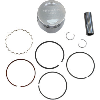 Silver cylindrical piston with engraved numbers, black piston rings, metal clips, and a shiny metal pin arranged on white.