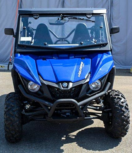 A Full UTV Cab by Open Trail is fitted on a blue Yamaha Wolverine side-by-side, parked on pavement and viewed from the front, highlighting its rugged tires, windshield, two seats, and durable features for comfort.