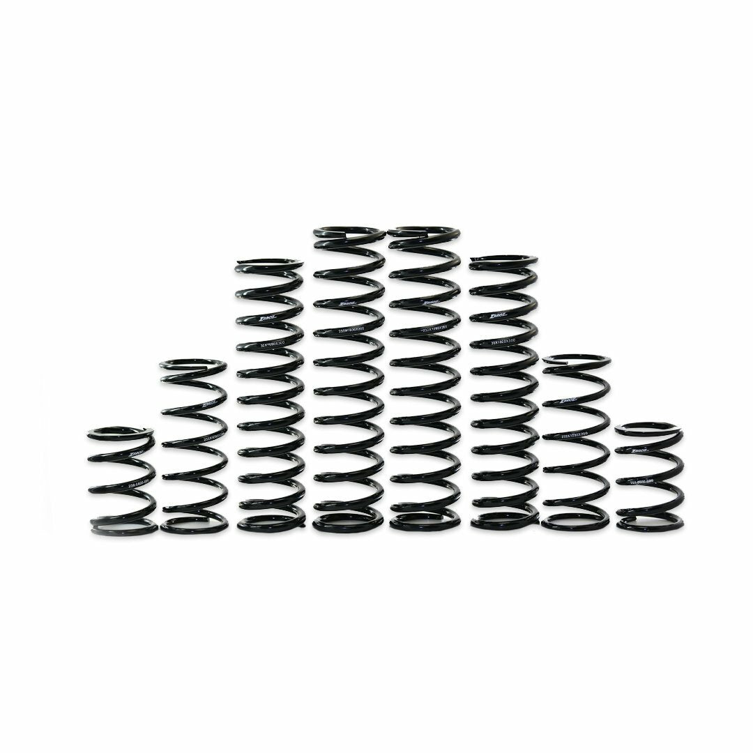 Seven black coil springs from the Kawasaki Dual Rate Spring Kit by ZBroz are arranged by height in a symmetrical row on a white background, demonstrating increased bottoming resistance and improved ride height.