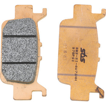Two Brake Pads by Sbs are shown side by side—one reveals the friction surface with two grooves for better brake feel, while the other displays the flat metal backing featuring printed text and a logo.