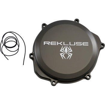The Honda Clutch Cover by Rekluse is a black billet aluminum cover featuring a white spider logo and lettering, shown next to a black gasket on a white background, and offers increased oil capacity for improved performance.
