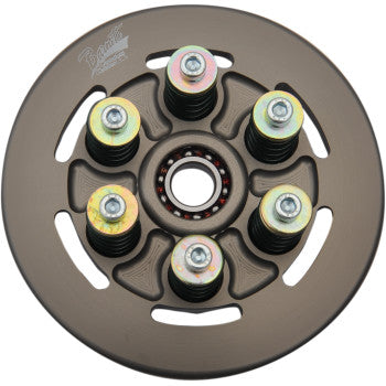 A round, metallic clutch plate from the Barnett Spring Conversion Kit features six bolt-spring assemblies in a circle around a central bearing. The dark brown plate has a logo and multiple cutout slots.