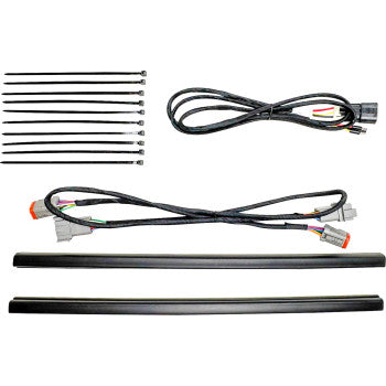 Black wiring harness with multiple connectors, eight black zip ties, and two black plastic mounting strips laid out on white