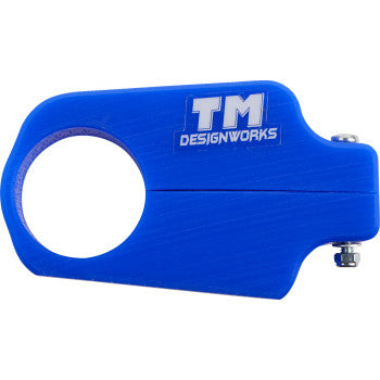 The Yamaha Front Chain Slider Blue by T.M. Designworks is a durable blue plastic slider with a large circular opening, curved shape, small metal bolt on the right edge, and "TM DESIGNWORKS" in white text.