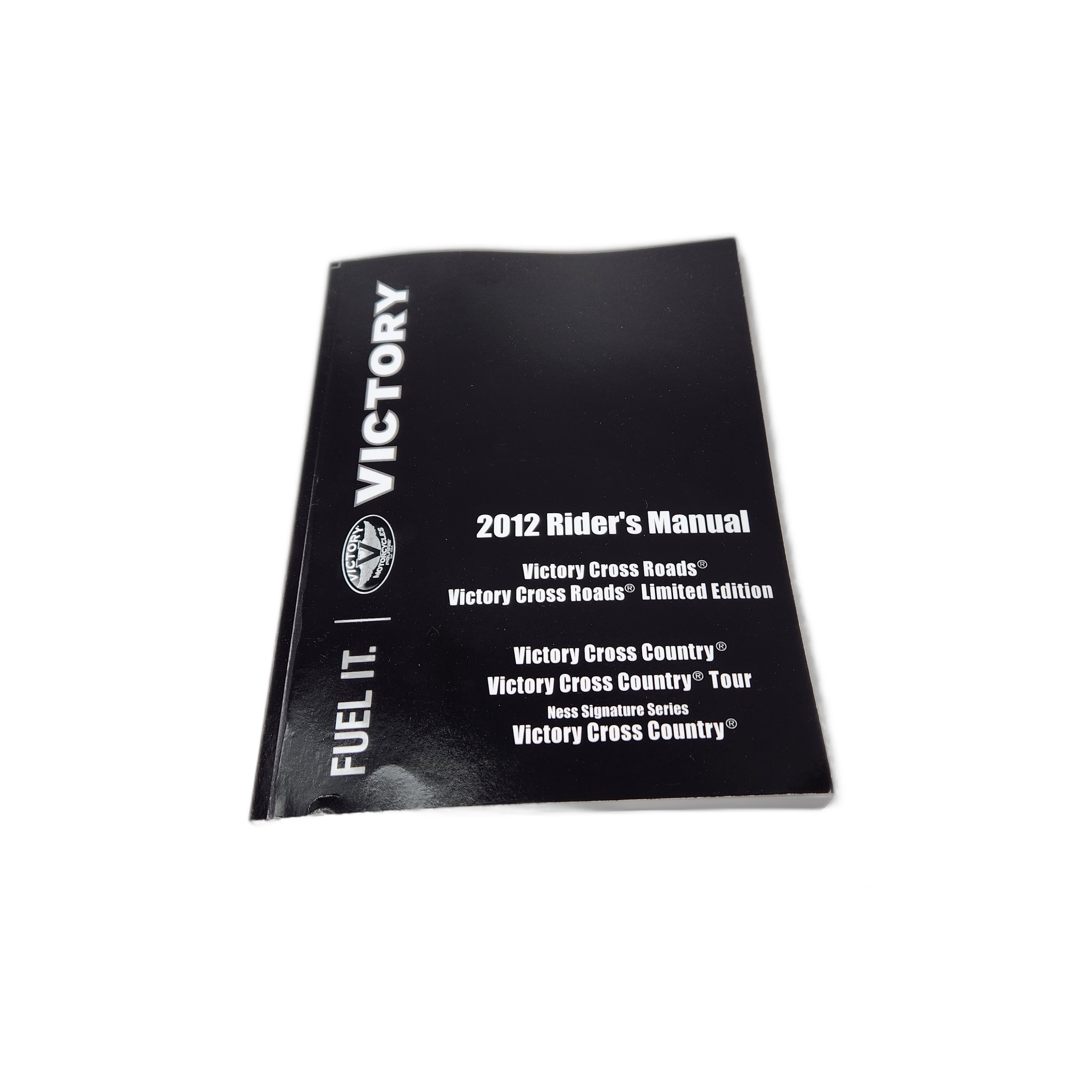 A black 2012 Owner’s Manual for Cross Roads and Cross Country motorcycles by Polaris is placed on a white surface. The cover displays the Victory logo, making it an essential reference for Victory motorcycle OEM parts.