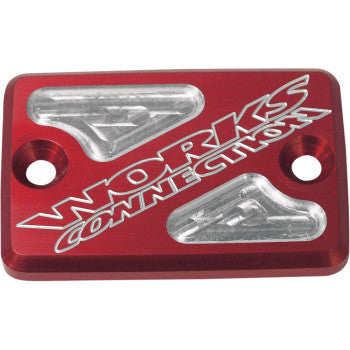 The ATV Billet Front Brake Reservoir Cover Red by Works Connection features aircraft-grade aluminum, a rectangular design with two screw holes, silver geometric accents, and engraved WORKS CONNECTION text.