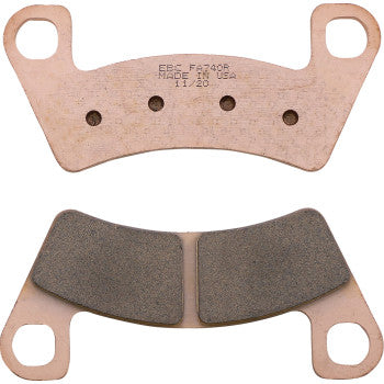 Copper-colored sintered brake pads with black friction material, curved rectangular shape with mounting holes.