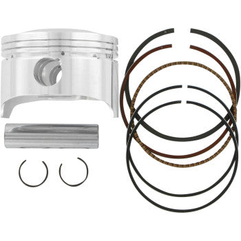 Silver metallic cylindrical piston, wrist pin, two circlips, and set of black and bronze piston rings arranged separately.