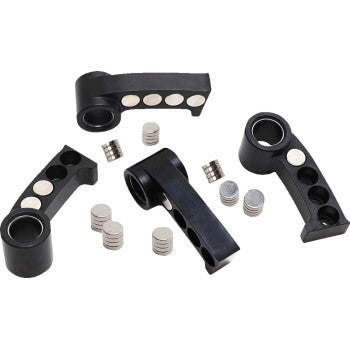 Three black plastic magnetic holders with circular holes are arranged with stacks of silver round magnets from the Clutch Weight Kit by S&S Cycle scattered around them on a white background.