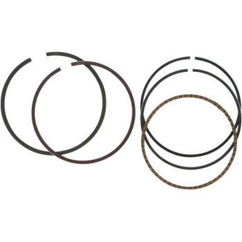 Four black circular rings and one metallic, textured ring from the Ring Set by Wiseco are arranged on a plain white background, highlighting quality components designed for Wiseco pistons.
