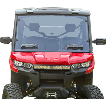 A front view of a red off-road utility vehicle with a Can-Am Defender Vented Windshield by Seizmik, built-in vents, side mirrors, rugged tires, and a horizontal LED light bar above the front bumper.