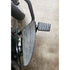 A close-up of the Adjustable Foot Rest Kit Anti Vibration Style by Witchdoctors on a concrete floor, highlighting its textured surfaces and part of a motorcycles rear tire.